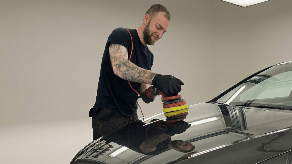 Detailer die een donkere auto polijst met een Rupes polijstmachine