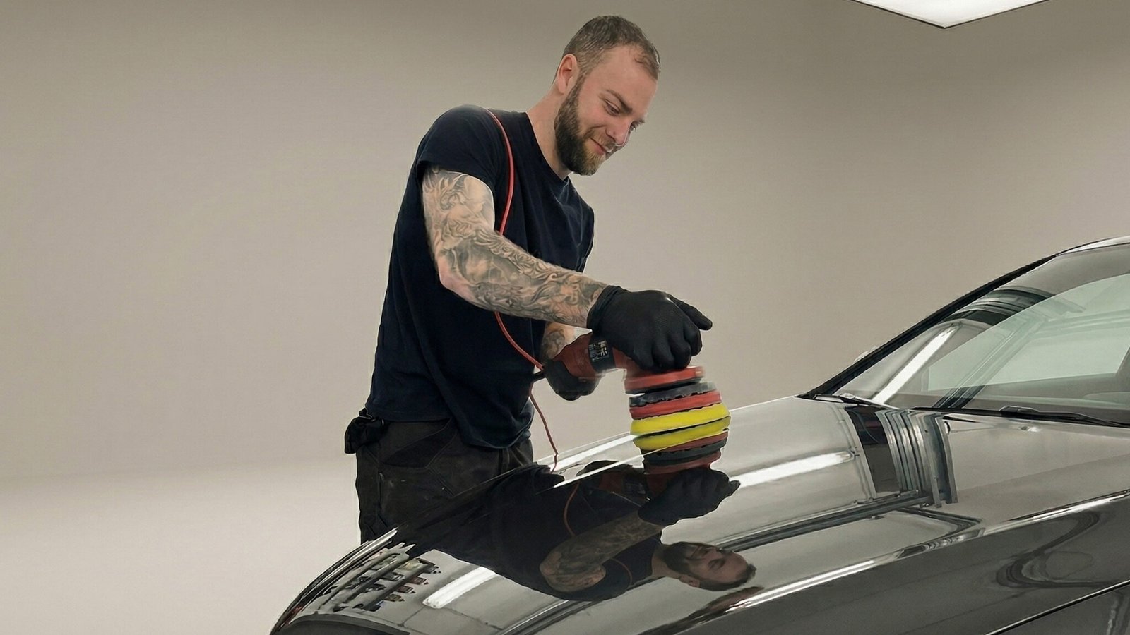 Detailer die een donkere auto polijst met een Rupes polijstmachine